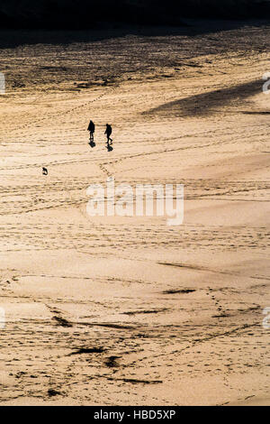 Zwei Personen gesehen, in der Silhouette und aus der Ferne auf dem preisgekrönten Crantock Beach in Newquay, Cornwall. Stockfoto