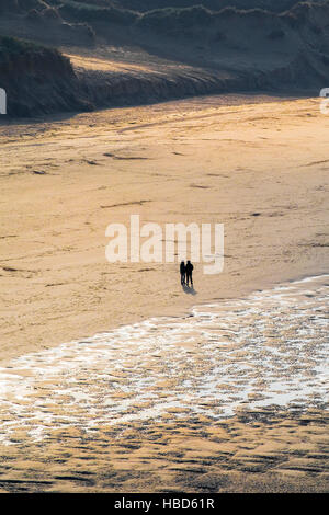 Zwei Personen gesehen, in der Silhouette und aus der Ferne auf Crantock Beach in Newquay, Cornwall. Stockfoto