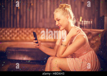 Zusammengesetztes Bild der schönen Frau auf dem Sofa sitzen und mit Handy Stockfoto