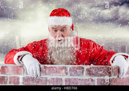 Zusammengesetztes Bild des Weihnachtsmannes spähen über Mauer Stockfoto