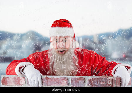 Zusammengesetztes Bild des Weihnachtsmannes spähen über Mauer Stockfoto