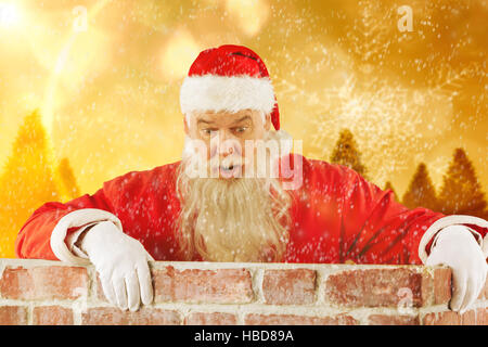 Zusammengesetztes Bild des Weihnachtsmannes spähen über Mauer Stockfoto