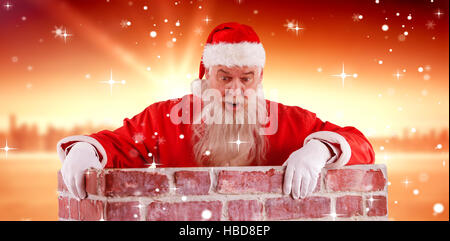 Zusammengesetztes Bild des Weihnachtsmannes spähen über Mauer Stockfoto