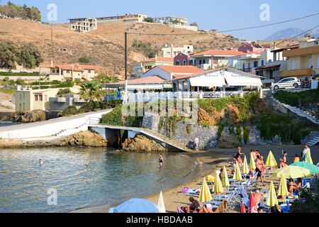 Touristen Entspannung am Sandstrand mit Blick auf die Stadt, Panormos, Kreta, Griechenland, Europa. Stockfoto