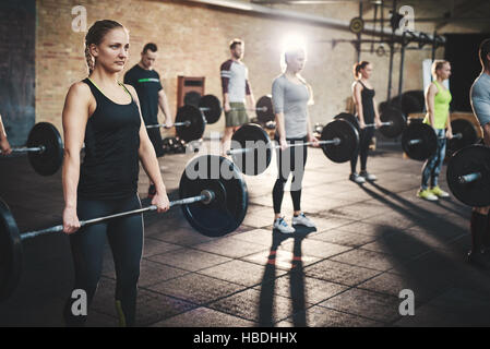 Gruppe von starken männlichen und weiblichen Erwachsenen schwere Hanteln in Fitness Übung Studio mit dicken Matten über Stock und Stein Wände halten Stockfoto