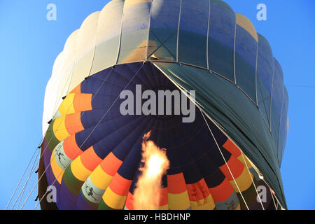 Flamme Erwärmung einen Heißluftballon, wie es in einem klaren blauen Himmel ragt Stockfoto