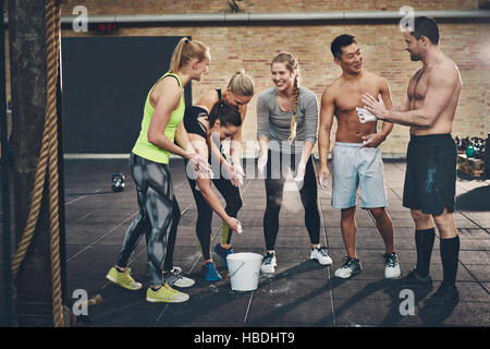 Muskulös und freundliche Gruppe von sechs athletische Männer und Frauen reden beim Anwenden von Talkum-Puder auf Hände zuvor intensive Trainingseinheiten erfordern eine Firma Stockfoto