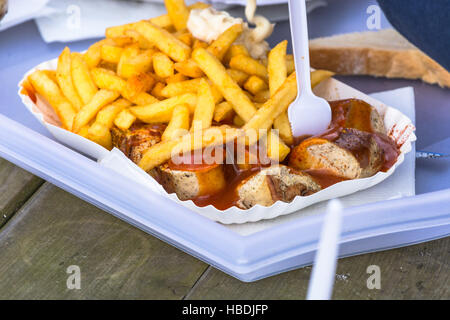 Papiertüte mit Currywurst und Pommes frites Stockfoto