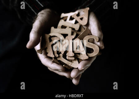 Nahaufnahme von einem alten kaukasischen Mann mit einem Haufen von Holzbuchstaben in den Händen, einige von ihnen bilden das Wort Xmas Stockfoto