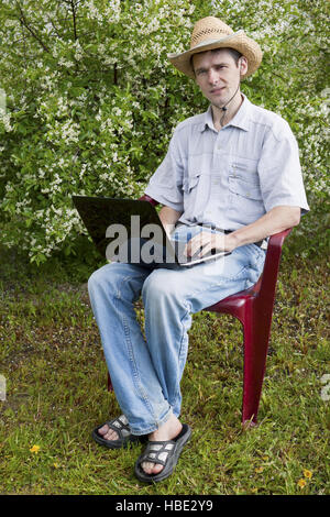 Ein junger Mann in einem Kirschbaum Garten Stockfoto