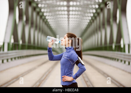 Junge Läufer ruhen, Trinkwasser auf grüne Stahlbrücke Stockfoto