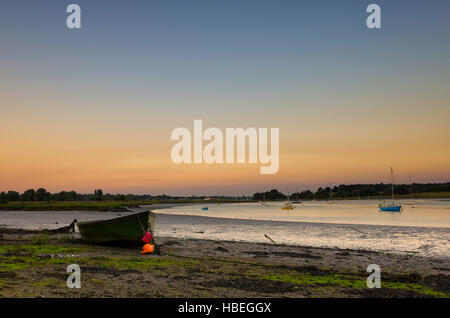 River Deben Woodbridge, England. Ein kleines Boot geerdet am Ufer des Flusses Deben in der Dämmerung. Der Himmel ist blau mit orange knapp über dem Horizont, der auf dem Wasser spiegelt. Dieses Foto wurde kurz nach dem Sonnenuntergang, das macht ein schönes weiches Licht während der frühen Dämmerung genommen. Stockfoto