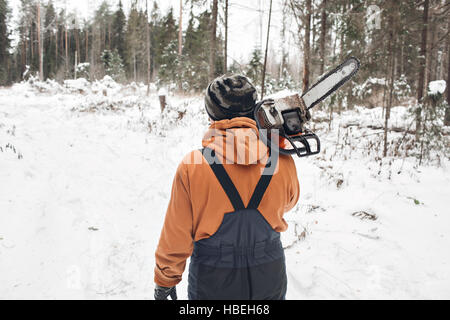 Professionelle Holzfäller halten Hand sah. Winter Kleidung Schutz mit Kettensäge. umgestürzte Bäume zu reinigen. Stockfoto