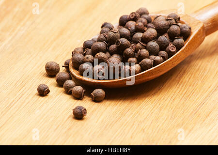 Piment, Pimenta Dioica in einem Holzlöffel auf hölzernen Hintergrund Stockfoto