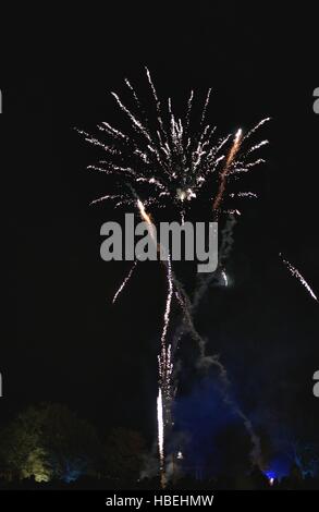 Glänzend natürliche Feuerwerk auf dunklen schwarzen Himmelshintergrund mit ein wenig Rauch. Menschen-Silhouetten unten. Stockfoto