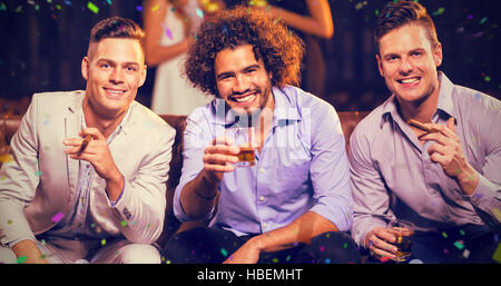 Zusammengesetztes Bild der drei happy Friends mit Zigarre und Whisky in der Bar Stockfoto