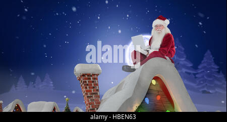 Zusammengesetztes Bild von Santa sitzt und einen laptop Stockfoto