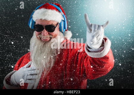 Zusammengesetztes Bild des Weihnachtsmannes Horn Anzeichen beim Musikhören über Kopfhörer Stockfoto