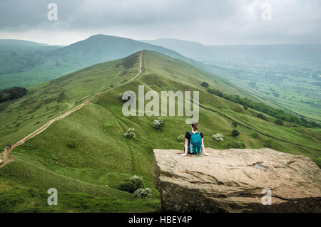 Frau sitzt auf einem Felsvorsprung, Peak District, Derbyshire, UK. Stockfoto