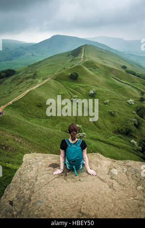 Frau sitzt auf einem Felsvorsprung, Peak District, Derbyshire, UK. Stockfoto