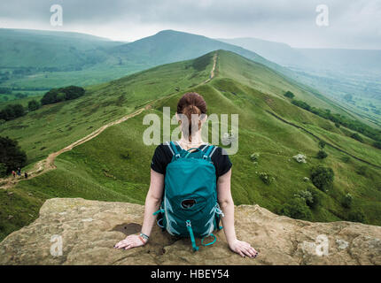 Frau sitzt auf einem Felsvorsprung, Peak District, Derbyshire, UK. Stockfoto