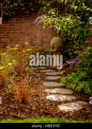 Stepping Steinpfad durch Garten Blumenbeet mit Rinde Splitt und Mauer Stockfoto