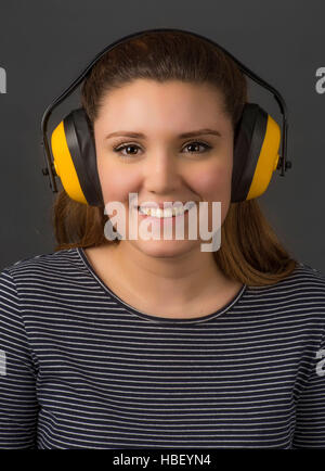Junge Frau trägt gelbe Gehörschutz für Gehörschutz. Stockfoto