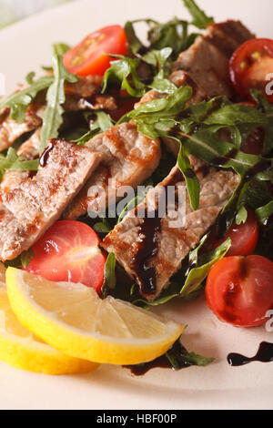 Warmer Salat von gegrilltem Rindfleisch mit Rucola und Tomaten Makro auf einem Teller. vertikale Stockfoto