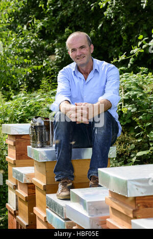 Imker mit Smoker sitzen auf Nesselsucht Stockfoto