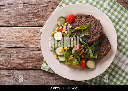 Schwarze Bohnen-Burger mit Salat aus frischem Gemüse Nahaufnahme auf einer Platte. Horizontale Ansicht von oben Stockfoto