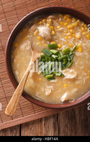 Chinesische Dicke Maissuppe mit Hühnerfleisch hautnah in eine Schüssel geben. vertikale Ansicht von oben Stockfoto