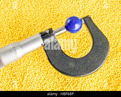 Mikrometer mit Perlen und Kugeln. Bunte Kunststoffperlen und einem Mikrometer messen eine Kunststoff-Kugel Stockfoto