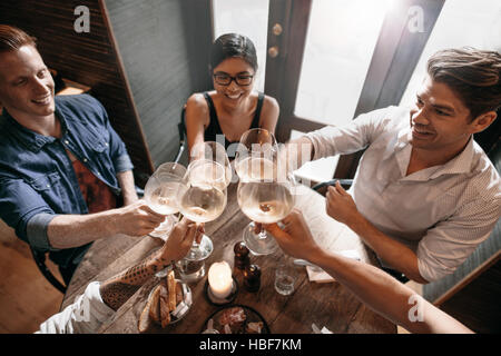 Draufsicht der jungen Männer und Frauen sitzen in einem Restaurant und Wein toasten. Gruppe von Personen, die bei einem Glas Wein im Café. Stockfoto