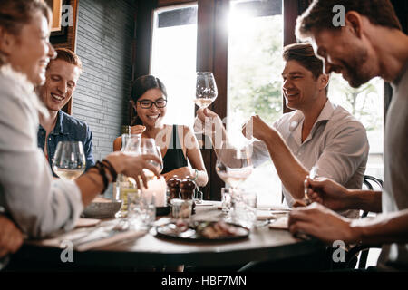 Junger Mann sein Glas Wein mit Freunden im Restaurant. Junge Menschen, Abendessen in einem Café zu genießen. Stockfoto