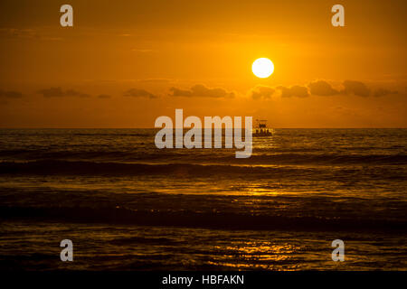 Ein Fischerboot kehrt in Saint-Gilles-Les-Bains am La Reunion bei Sonnenuntergang. Stockfoto