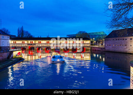 Ausflugsschiff mit Touristen vor der Barrage Vauban (Vauban-Wehr) nachts entlang dem Fluss Ill, Straßburg, Frankreich Stockfoto