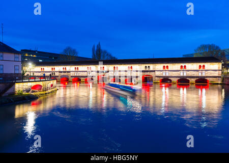 Ausflugsschiff mit Touristen vor der Barrage Vauban (Vauban-Wehr) nachts entlang dem Fluss Ill, Straßburg, Frankreich Stockfoto