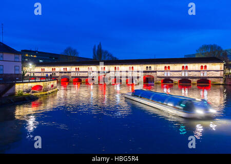 Ausflugsschiff mit Touristen vor der Barrage Vauban (Vauban-Wehr) nachts entlang dem Fluss Ill, Straßburg, Frankreich Stockfoto