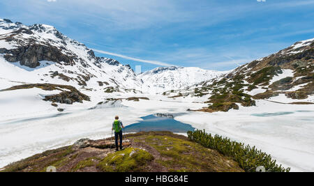 Junger Mann, Wanderer, Blick auf zugefrorenen See, Unterer Giglachsee, Berglandschaft mit verbleibenden Schnee, Rohrmoos-Obertal Stockfoto