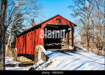 Pool Forge rot überdachte Brücke Weihnachtslichter im Freien Dekorationen Lancaster County, Pennsylvania, USA, ländliche deutsche Amish Schnee-Szene Stockfoto