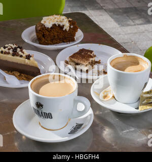 Zwei Tassen Kaffee und drei Kuchen auf einem Holztisch Stockfoto