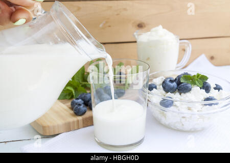 Gießen Milch in das Glas auf dem Tisch Stockfoto