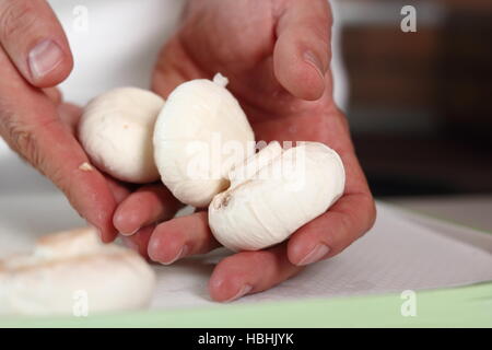 Koch hält Champignons in der hand. Huhn, Käse und Lauch-Paket-Serie zu machen. Stockfoto