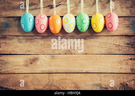 Bunte Ostereier an rustikalen hölzernen Hintergrund mit Raum hängen. Ostern Eiern Hintergrund. Stockfoto