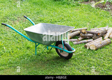 Sackkarre mit Brennholz auf dem grünen Rasen Stockfoto