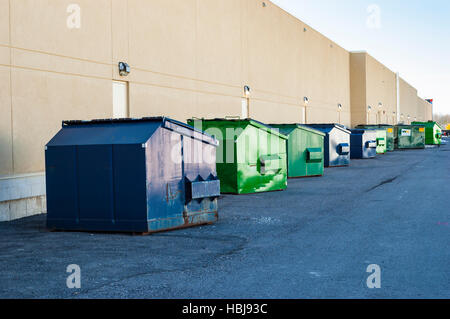 Blau und grün, die industrielle Mülltonnen aufgereiht außen entlang Geschäftshaus Stockfoto