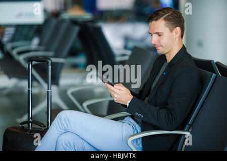 Junger Mann mit Handy innen im Flughafen. Junger Mann mit Smartphone am Flughafen beim Boarding warten. Stockfoto