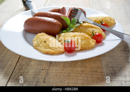 Gebratene Würstchen und panierte Kartoffeln Stockfoto