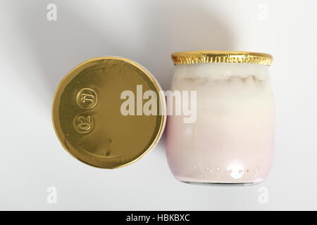 Joghurt in kleinen Glas mit Aluminium Folie Dichtungskappe. Isoliert auf weißem Hintergrund. Stockfoto