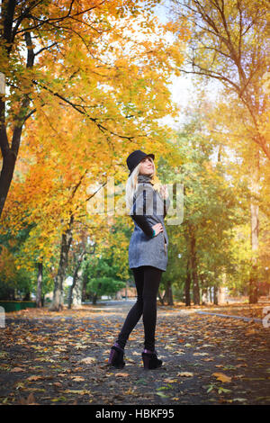 Wunderschöne stilvolle junge Frau tragen modische Kleidung. Porträt von Mädchen in schwarzen Hut in der Gasse im Park. Stockfoto